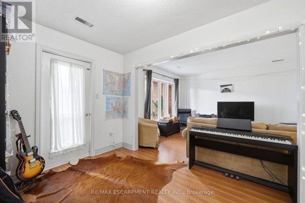 Living area with a piano, guitar, white door, and hardwood floors. - 277 Harvie Avenue, Toronto