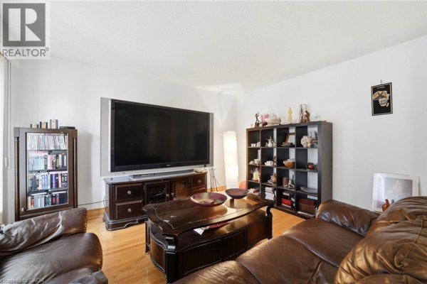 Living room with brown leather sofas, a large television, and shelving units. - 277 Harvie Avenue, York