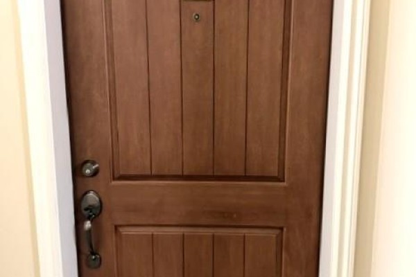 A close-up of a dark brown wooden apartment door with a black handle. - 2770 Auburn Road Unit# 107, West Kelowna