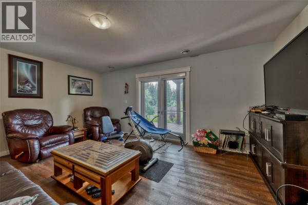 Kitchen with wooden cabinetry, island, and dining area, featuring tile flooring. - 2770 Perris Road, Blind Bay