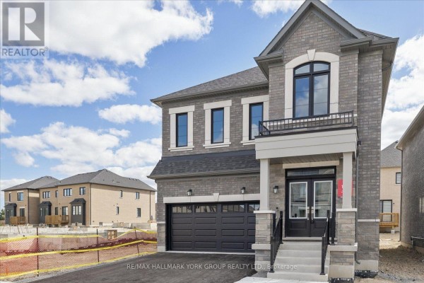 Side view of a grey brick house with a black garage door and arched window. - 278 Walter English Drive, East Gwillimbury