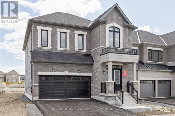 Front exterior of a grey brick house with a balcony above the entrance. - 278 Walter English Drive, East Gwillimbury