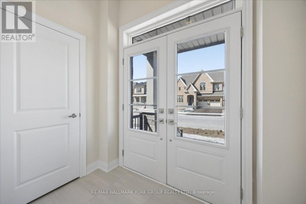 View through the glass front doors of a residential street with houses under construction. - 278 Walter English Drive, East Gwillimbury