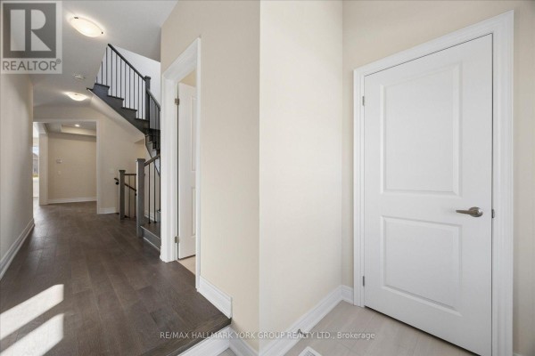 Interior hallway with dark wood flooring, white doors, and a staircase with black railing. - 278 Walter English Drive, East Gwillimbury