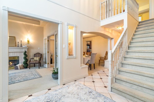 Foyer with a fireplace, staircase, and doorway leading to a dining area. - 2780 St Moritz Way, Abbotsford