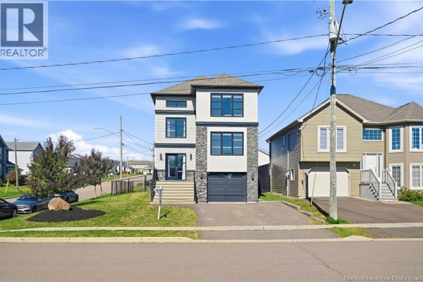 Front view of a contemporary house with light siding, stone accents, and an asphalt driveway. - 279 Freeman, Moncton