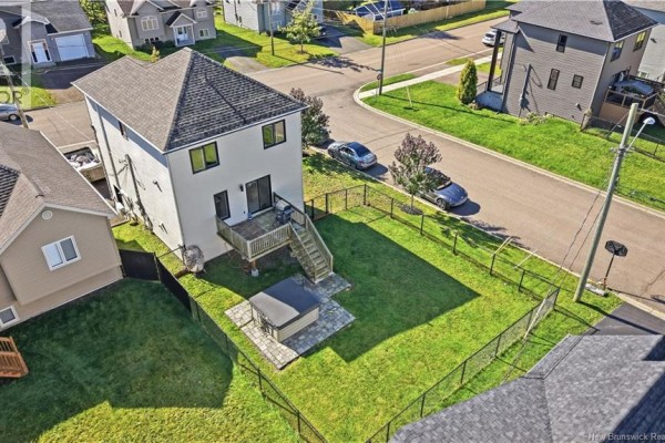 Rear aerial view of a house showing a wooden deck, hot tub, fenced lawn, and backyard. - 279 Freeman, Moncton