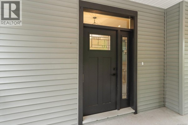 View through the open front door into a hallway, showing the porch exterior. - 279 Westwood Rd, Nanaimo