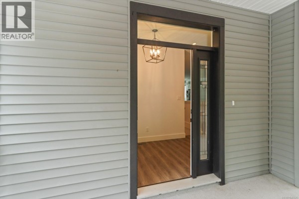 Interior view of the entryway with white walls, wood-look flooring, and double bi-fold doors. - 279 Westwood Rd, Nanaimo