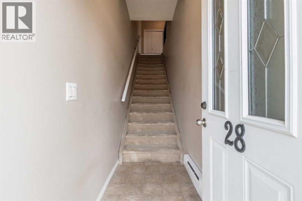 Interior view of townhouse entryway showing a staircase leading upwards. - 28, 298 Somerset Way Se, Medicine Hat