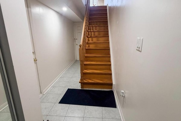 Interior hallway with light grey tiled floor, white walls, and a wooden staircase. - 28 - 1525 South Parade Court, Mississauga