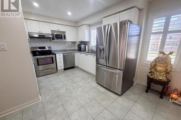 Modern kitchen with white cabinetry, stainless steel appliances, and tile flooring. - 28 - 1525 South Parade Court, Mississauga