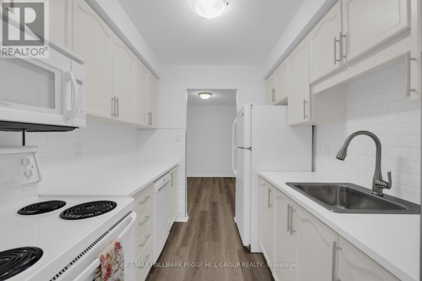 White galley kitchen with white subway tile backsplash, laminate flooring, and white appliances. - 28 - 165 Kozlov Street, Barrie