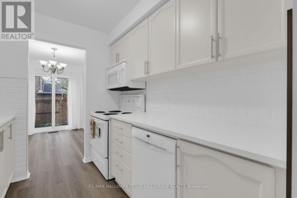 White kitchen cabinets and countertops with white subway tile backsplash and stove. - 28 - 165 Kozlov Street, Barrie