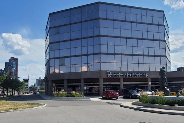 Corner view of a modern glass-faced office building with Red Lobster on the ground floor. - 28 - 3200 Dufferin Street, Toronto