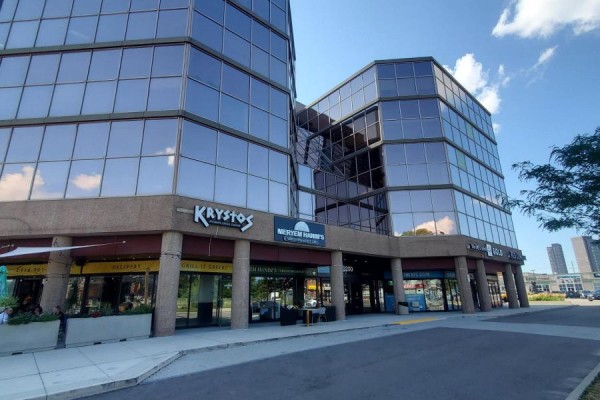 Side view of a multi-story glass office building with various businesses on the ground floor. - 28 - 3200 Dufferin Street, Toronto