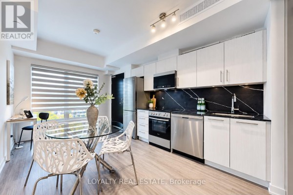 Open concept living space with glass dining table, chairs, and modern kitchen. - 28 - 861 Sheppard Avenue W, Toronto
