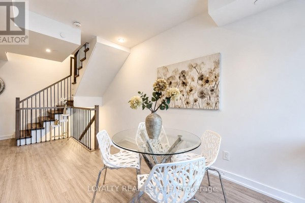 Dining area with glass table and chairs, adjacent to staircase with dark railings. - 28 - 861 Sheppard Avenue W, Toronto