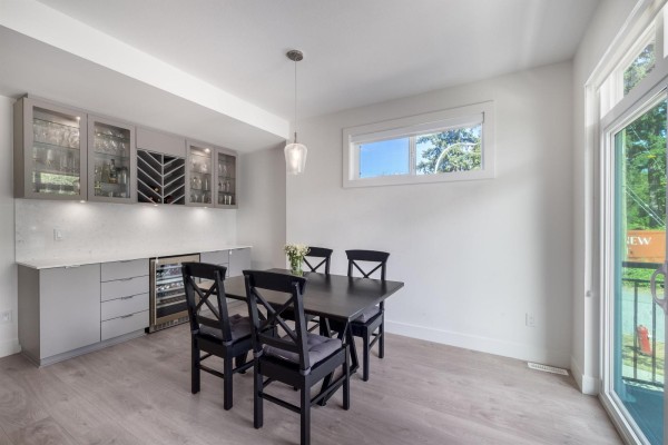 Dining area with a black table and chairs, and a built-in bar with wine fridge. - 28 16561 17a Avenue, Surrey