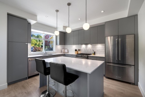 Island kitchen with grey cabinetry, stainless steel appliances, and pendant lighting. - 28 16561 17a Avenue, Surrey