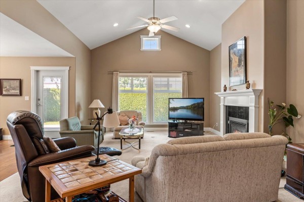 Living room with vaulted ceilings, a fireplace, a television, and plush seating. - 28 45752 Stevenson Road, Sardis South, Chilliwack