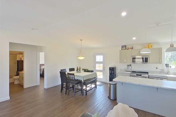 Open-concept living area with dining table, kitchen island, and view into hallway. - 28-590059 Range Road 110, Rural Woodlands County