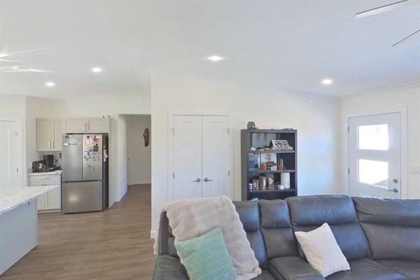 Living room with large leather sofa, entertainment unit, and doorway to kitchen. - 28-590059 Range Road 110, Rural Woodlands County