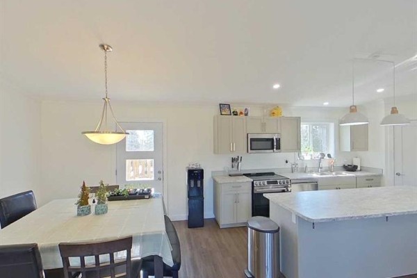 Dining area and kitchen with light grey cabinets, stainless steel appliances, and island. - 28-590059 Range Road 110, Rural Woodlands County