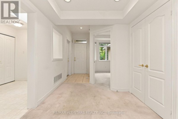 Interior entryway with beige carpet, white walls, and a view into a sunroom. - 28 Blue Heron Beach Way, Markham