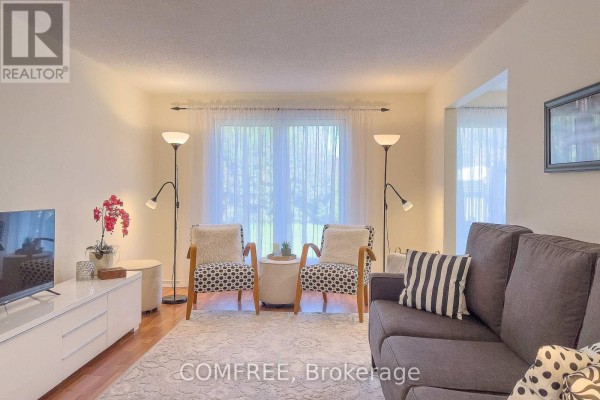 Living room with grey sofa, patterned armchairs, and white sheer curtains. - 28 Bluejay Drive, Barrie