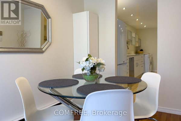 Glass dining table with white chairs and a silver octagonal mirror. - 28 Bluejay Drive, Barrie
