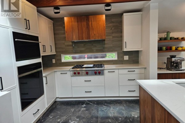 Modern kitchen with white cabinetry, stainless steel appliances, a gas range, and a stone tile backsplash. - 28 Burnbank Street, Ottawa
