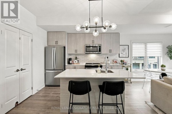 Kitchen view with light wood cabinets, island with seating, and open concept living space. - 28 Canton Lane, Whitchurch Stouffville