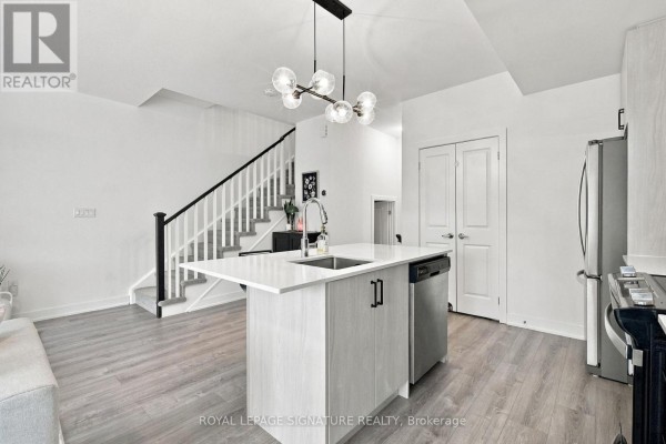 Kitchen with island, stainless steel dishwasher, and view of stairs leading to upper floor. - 28 Canton Lane, Whitchurch Stouffville