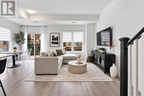 Living room with sectional sofa, coffee table, entertainment unit, and a view of the dining area. - 28 Canton Lane, Whitchurch Stouffville