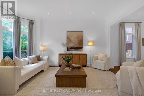 Living room with hardwood floors, purple tufted sofas, and mirrored coffee table. - 28 Carnwath Crescent, Toronto