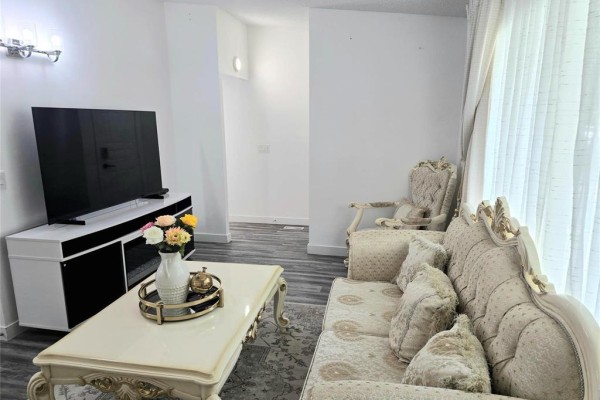 Living room with two sofas, armchair, coffee table, rug, and television on stand. - 28 Fairview Drive, Winnipeg