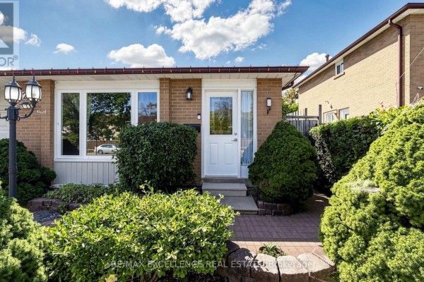 Close-up view of the front entrance with a white door, flanked by green shrubs. - 28 Glenvale Boulevard, Brampton