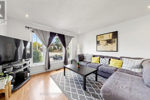 Living room with a sectional sofa, coffee table, TV, and a large window with curtains. - 28 Glenvale Boulevard, Brampton