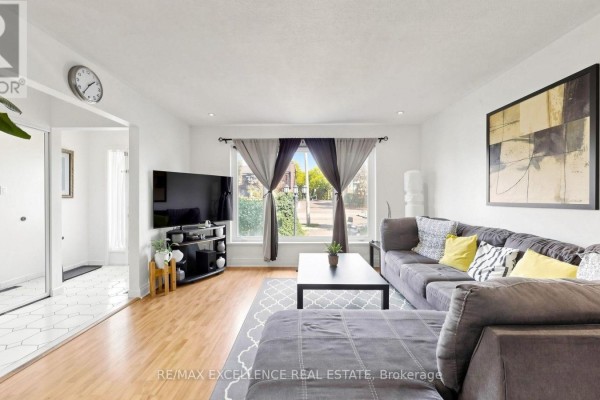 Living room showing the sectional sofa, TV, and entrance to a tiled hallway. - 28 Glenvale Boulevard, Brampton