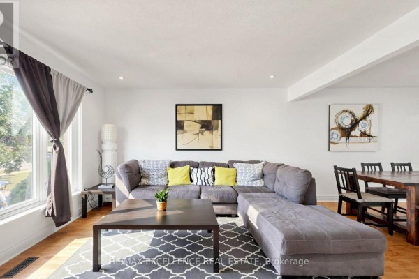 Living room with a sectional sofa, dining table, large window, and modern art on the walls. - 28 Glenvale Boulevard, Brampton