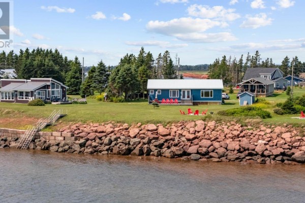 A teal-sided building with a wooden deck, red chairs, and surrounded by green grass. - 28 Gordons Way, Augustine Cove