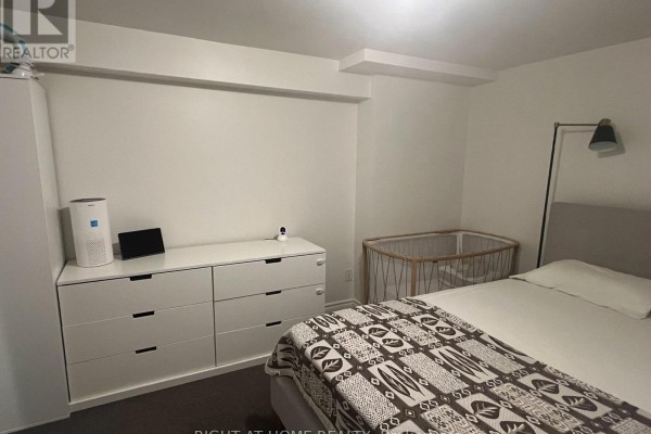 Bedroom with a white dresser, crib, and a bed with a patterned blanket and a floor lamp. - 28 Gorman Park Road, Toronto