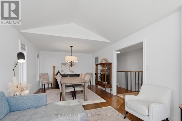 Living and dining area with vaulted ceiling, dining table, glass cabinet, and staircase view - 28 Hickory Grove Belleville