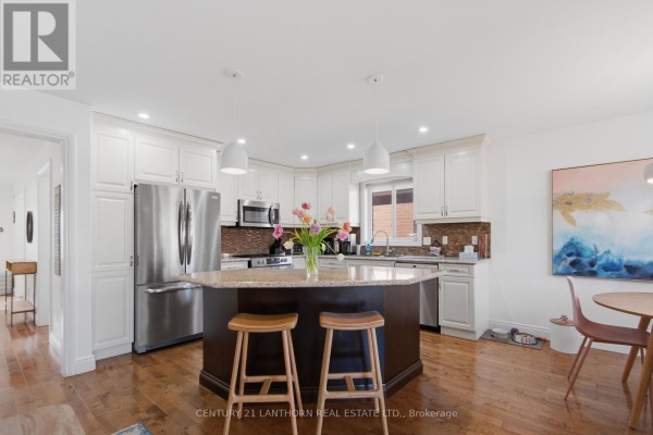 Kitchen with island, stainless steel fridge, and hardwood floors - 28 Hickory Grove Belleville