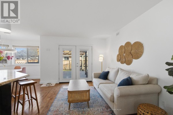 Living room with sofa, rattan coffee table, and kitchen island, leading to deck - 28 Hickory Grove Belleville