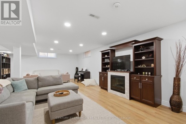Sectional sofa, fireplace, TV, and piano in finished basement living room - 28 Hickory Grove Belleville
