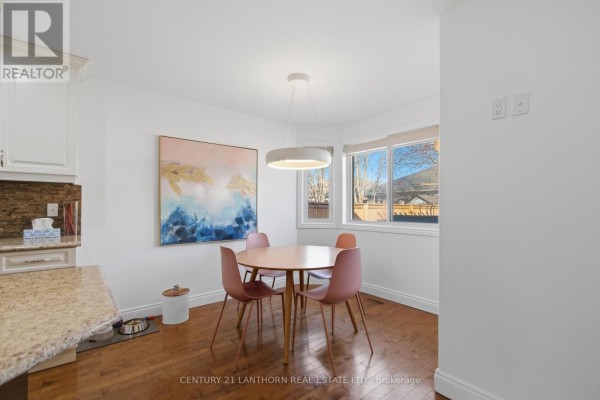 Dining area with round table, pink chairs, modern light, granite counter, and large windows - 28 Hickory Grove Belleville
