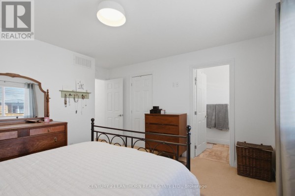 Bedroom with metal bed frame and wooden dresser, en suite bathroom visible - 28 Hickory Grove Belleville