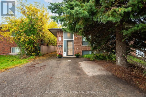 Side exterior view of a brick duplex with a glass front door and paved driveway. - 28 Hillside Drive, Orangeville